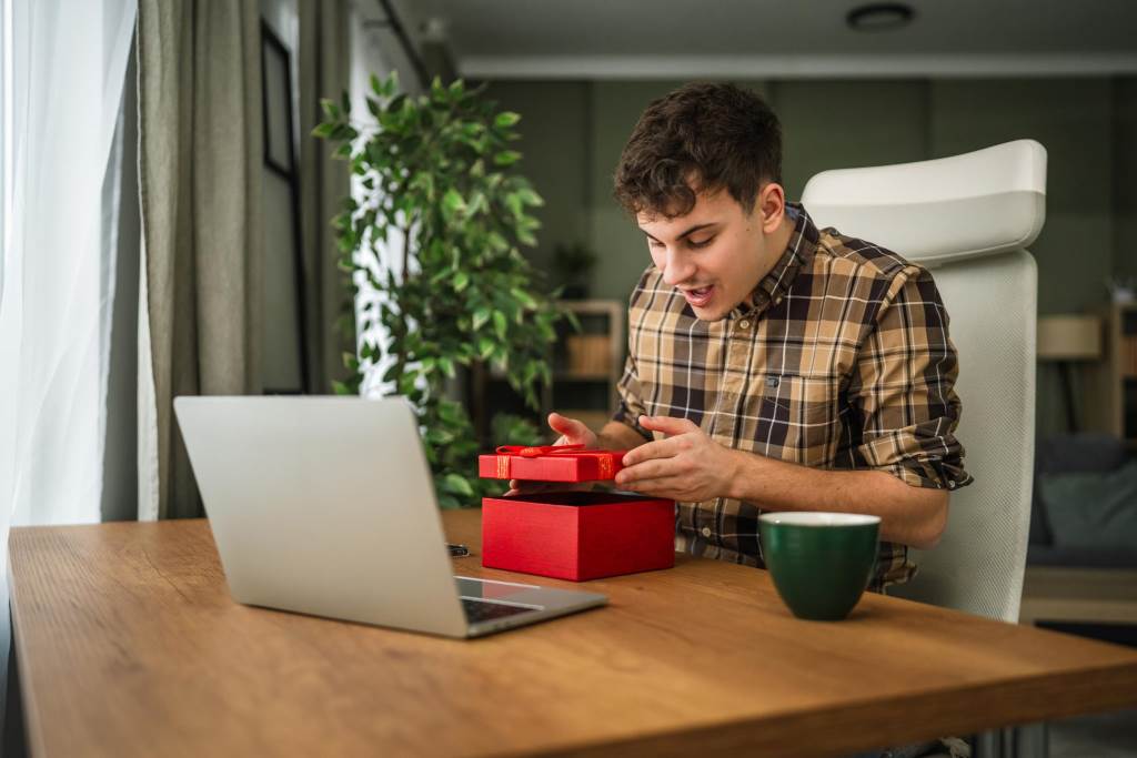 Excited man receiving surprise gift online using laptop