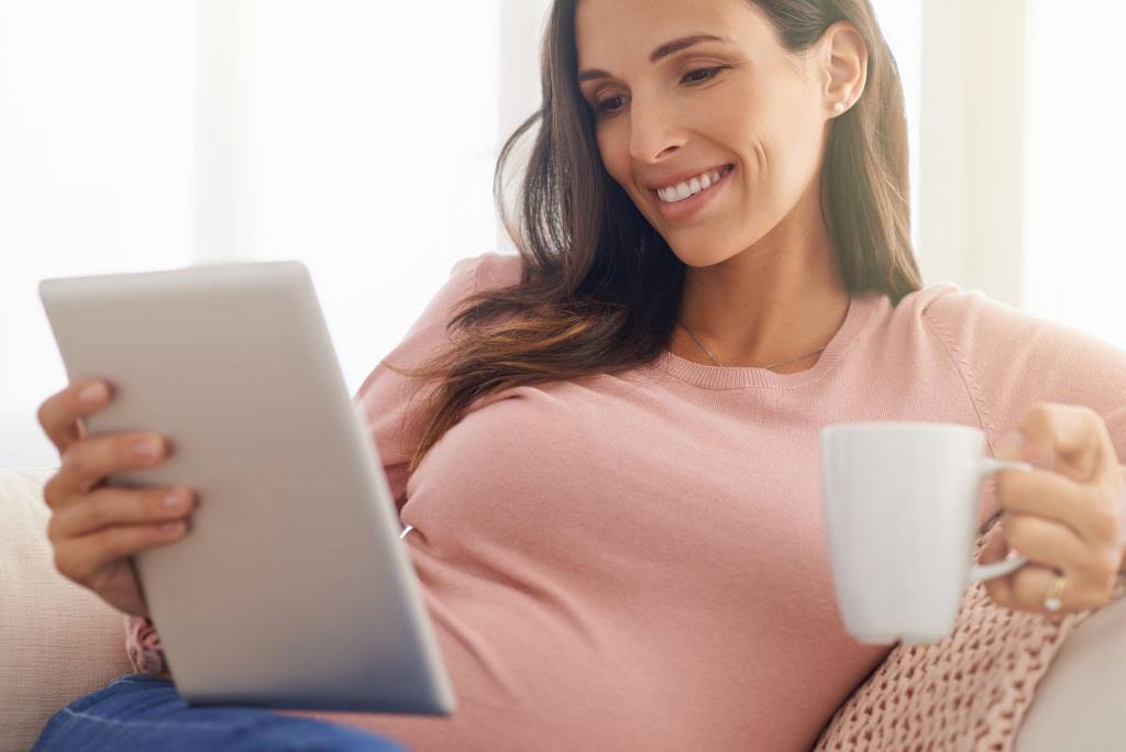 Expecting mom relaxing at home holding her baby bump