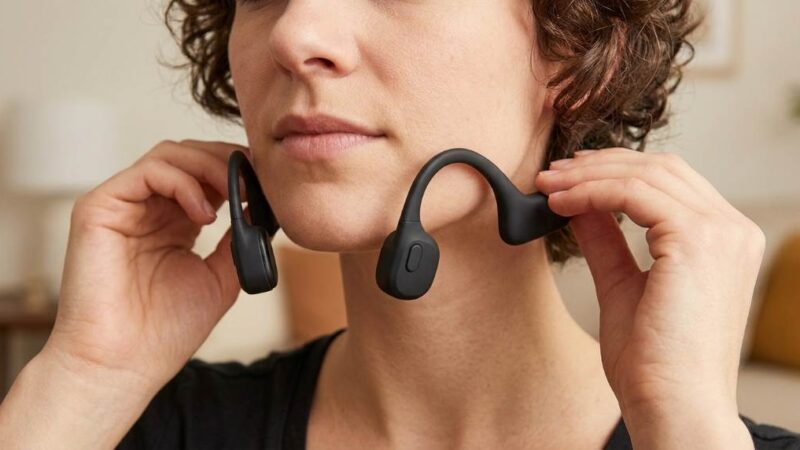 Person wearing bone conduction headphones while running in a park.