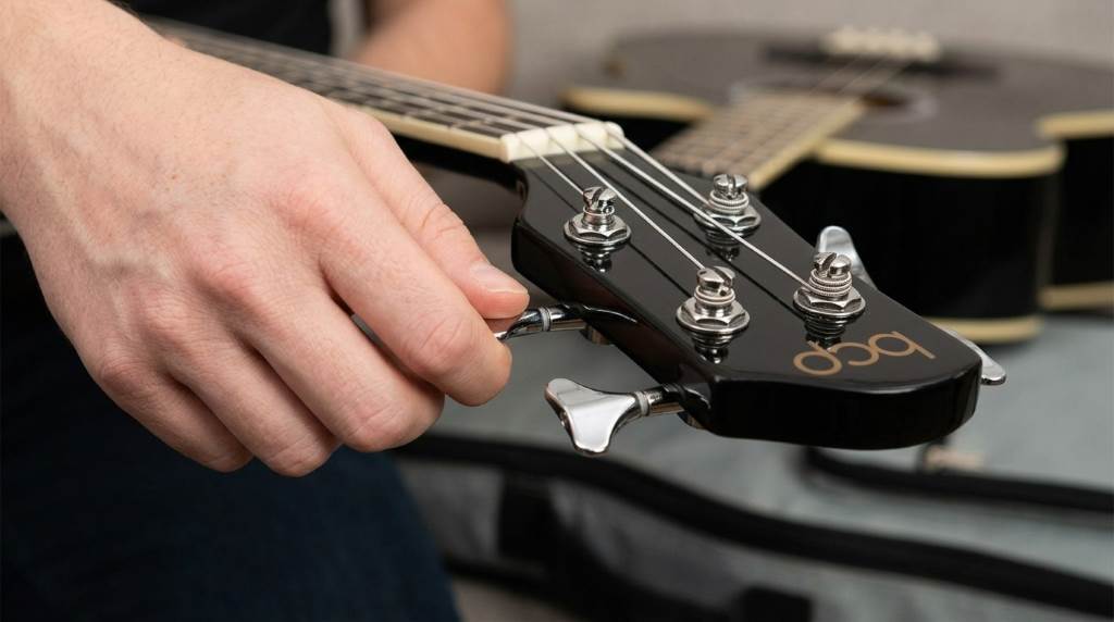 Player tuning a Choice Products bass guitar with electronic tuner